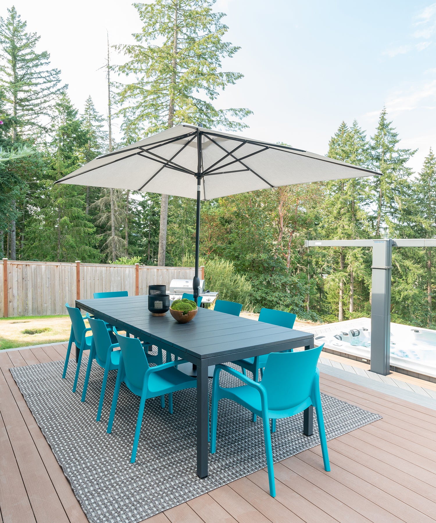 Blue chairs around an outdoor dining table underneath an umbrella on a backyard porch