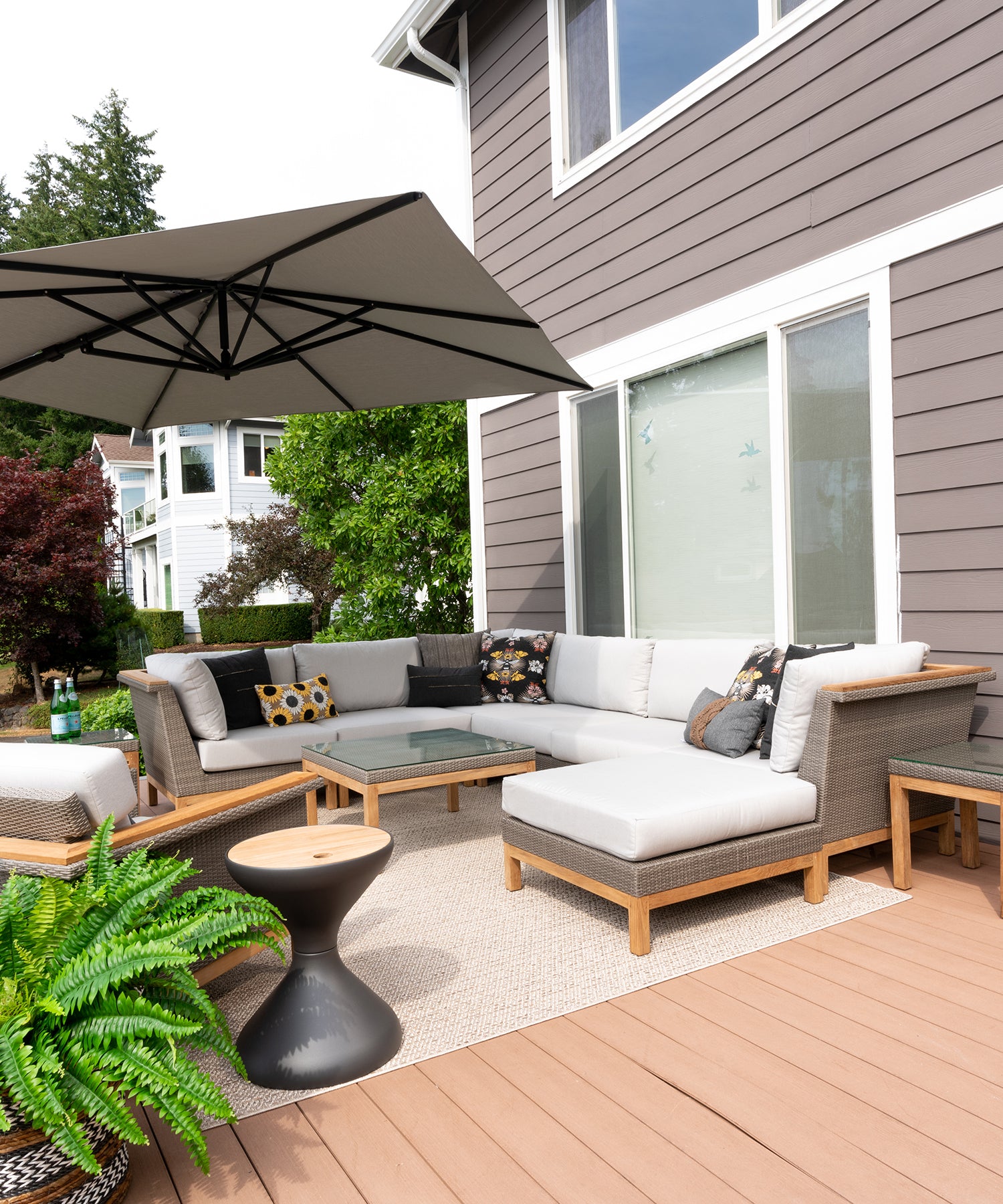An outdoor sectional with light grey cushions on a large porch