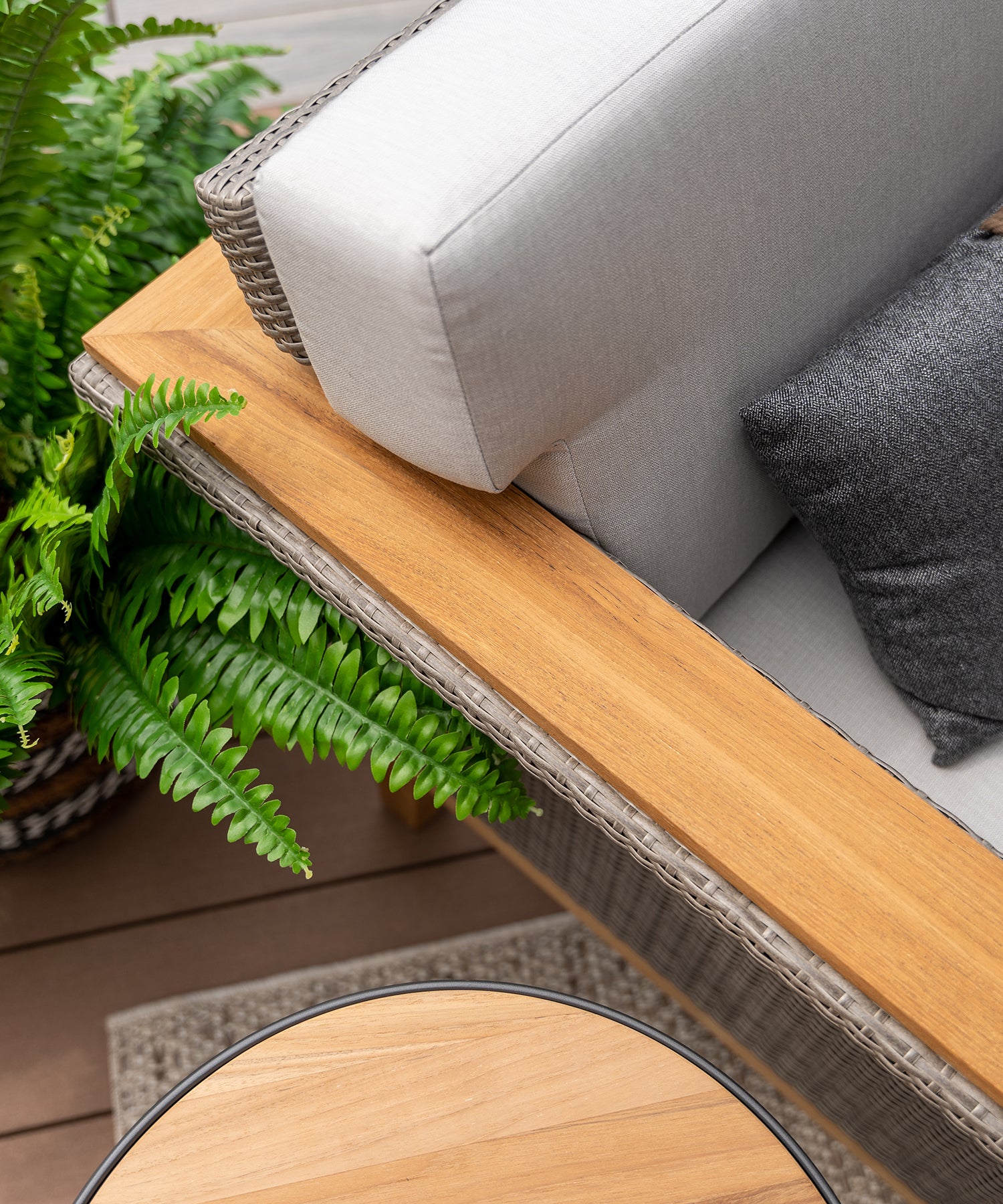 Close-up of teak arm on an outdoor chair with cushions