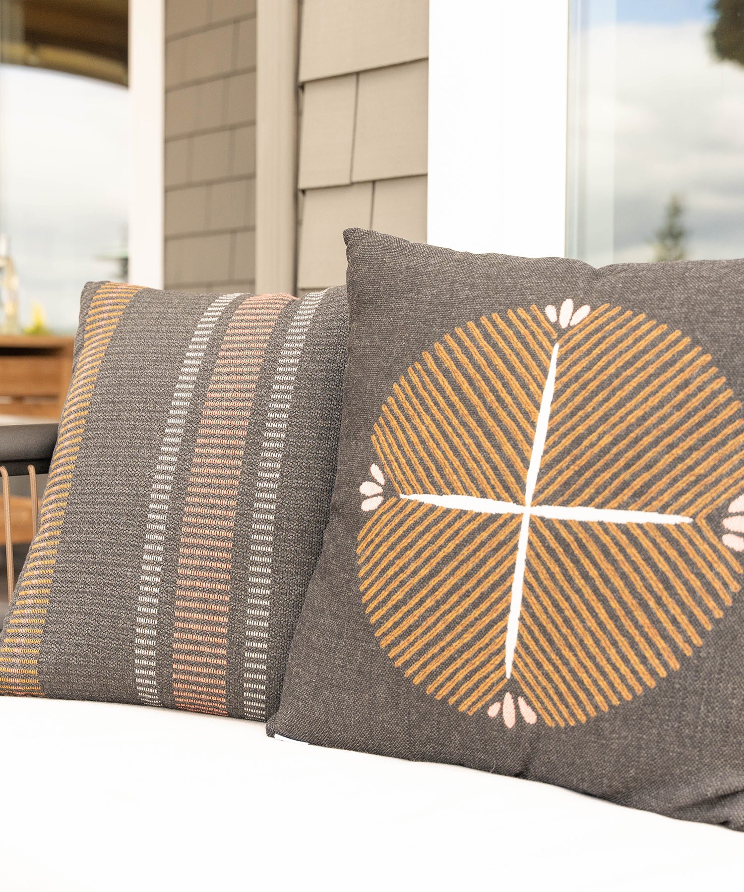 Close-up of two grey and orange outdoor throw pillows